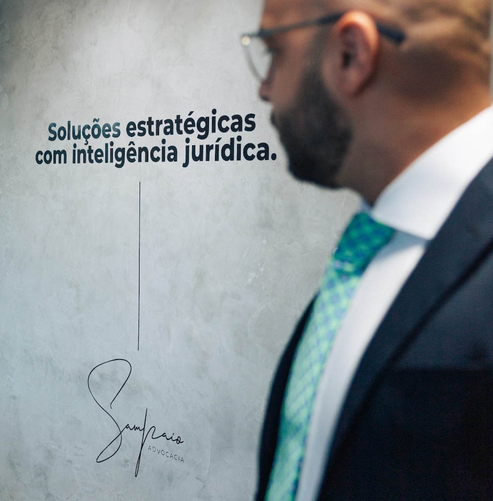 Leonardo Sampaio de perfil ao lado da parede com o slogan da Sampaio Advocacia, em Eunápolis