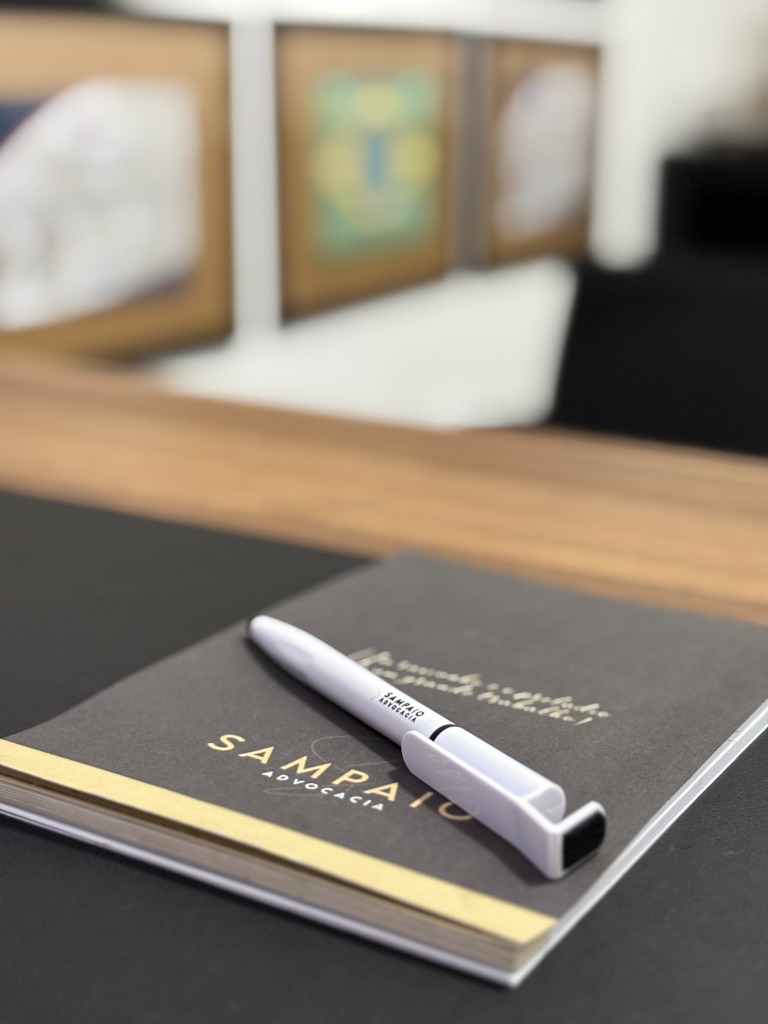 Caderno e caneta com a marca Sampaio Advocacia sobre a mesa do escritório